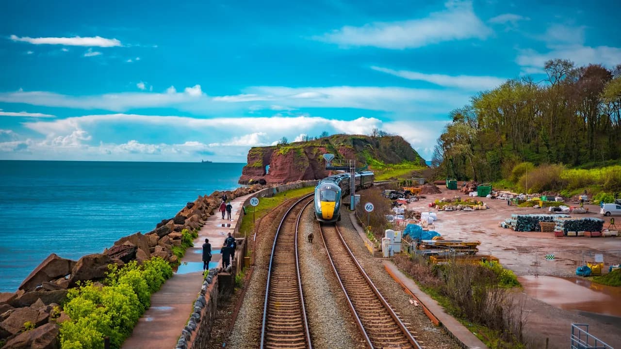 A Great Western Railway train running beside the sea wall walk under the red sandstone cliffs of the South Devon coast